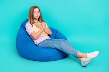 Wall Mural - Full length photo of pretty tired lady wear t-shirt bean bag cuddling book empty space isolated turquoise color background