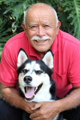 Wall Mural - Senior Hispanic man hugging his Siberian husky 