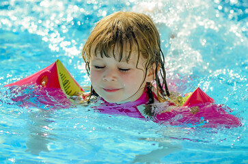 Wall Mural - Beautiful young girl playing in the pool with her arm bands