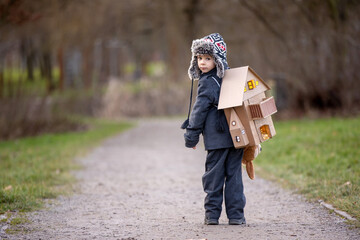 Little child, blond boy with pet dog, carying home on his back, kid, having paper house