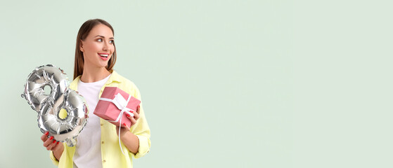 Wall Mural - Beautiful young woman with balloon in shape of figure 8 and gift on light background with space for text. International Women's Day celebration