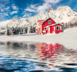 Wall Mural - red wooden houses reflected in the calm waters of norwegian sea. bright winter view of vestvagoy isl