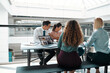 © Flamingo Images - Smiling businesspeople working at a table in an office building