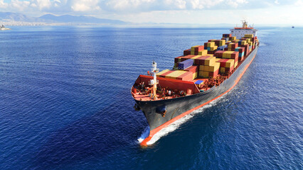 Aerial drone photo of truck size container cargo vessel cruising in deep blue sea near commercial port of Piraeus