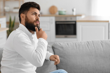 Sticker - Thoughtful young bearded man on sofa in kitchen