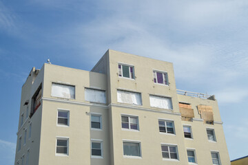 Tall apartment building with the windows near the top removed and the holes covered over