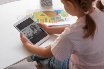 Canvas Print - Little girl video chatting with psychologist on tablet computer at home, closeup