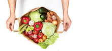 Female Hands Open A Paper Bag Filled With Various Vegetables Isolated On A White Background. Delivery And Purchase Of Healthy Eco Food