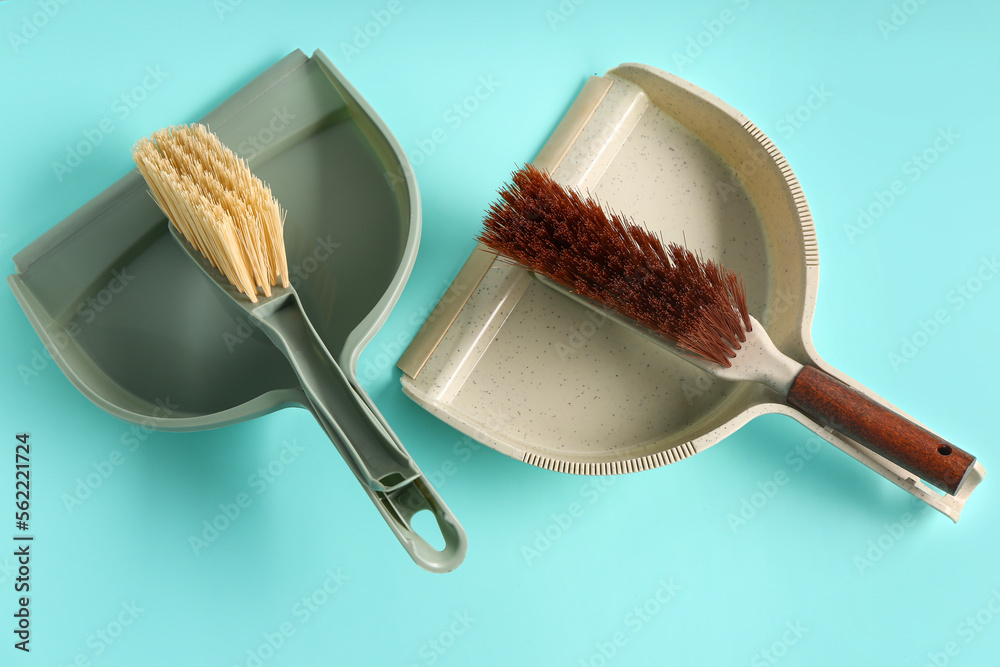 Dustpans and brushes on color background