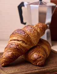 Canvas Print - Baked crispy croissant on a wooden board, breakfast