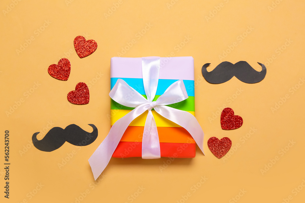 Gift with hearts and paper moustaches on beige background. Valentine's Day celebration