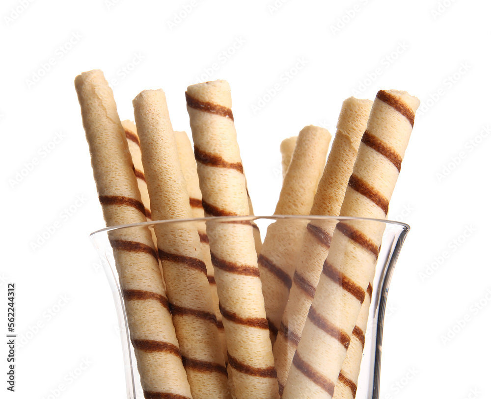 Glass of tasty wafer rolls on white background