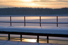Sunset Clouds Over Frozen Lake. Sunset Colors Reflection In Snow Covered Lake. Frozen Lake Pier On Sunset