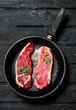 © Artem Shadrin - Raw beef steaks in an old pan with rosemary sprig.