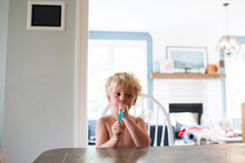 Shirtless boy having ice pops tube while sitting at home