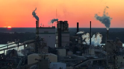 Poster - Aerial view of large factory with smokestack from production process polluting atmosphere at plant manufacturing yard. Industrial site at sunset