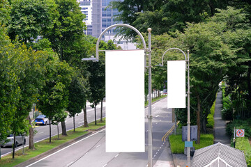 tall vertical hanging blank advertising banners posters mockup; lush plants and tress in background;