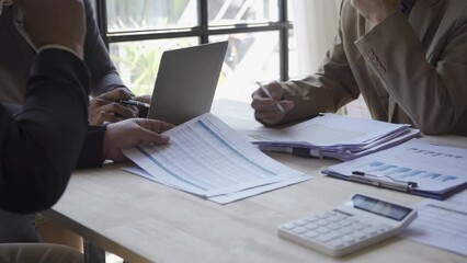 Wall Mural - Group of Asian businessmen brainstorming close-up at plan meeting statistical analysis and pointing graph employee taking notes with laptop on table finance business success statistics concept