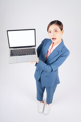 Wall Mural - Full length photo of young Asian businesswoman using laptop