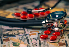 A Stethoscope With Pills And Dollars In Close-up.