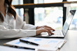 © bongkarn - Focused businesswoman using laptop, working on her financial tasks. cropped side view image