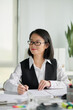 © DragonImages - Portrait of positive social consultant working with reports at office desk