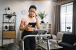 © sofiko14 - Confident muscular sporty businesswoman in headset working remote from home using digital tablet, while having cardio workout, running on treadmill.
