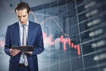 Poster - Attractive young european businessman using tablet with abstract falling red forex chart on blurry office interior background. Economic decline and loss concept.