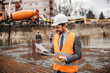 © dusanpetkovic1 - A contractor is looking at documents while standing on site.