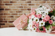 Beautiful bouquet of rose and chrysanthemums flowers and pink gift box on brick wall background. Gift for holiday, birthday, Wedding, Mother's Day, Valentine's day, Women's Day. Floral arrangement.