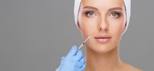 Wall Mural - Doctor injecting in a beautiful face of a young woman. Plastic surgery concept.