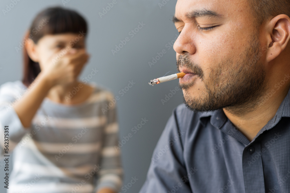 choking on a cigarette Photo Stock Husband smoking cigarette and wife choking of smoke. Man smoking  cigarette and woman is covering her face and a lot of smoke around smelling  pollution. Passive stop smoking cigarettes campaign. |
