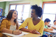 © Reese/peopleimages.com - Education, learning and teacher help student with assignment in elementary school. Classroom support, scholarship and happy black woman or educator aid, explaining and helping girl learner in class.