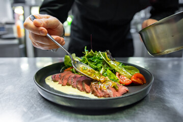 chef hand cooking Roast beef salad with vegetables on restaurant kitchen