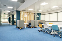 A Coworking Office With A Boardroom Table And Meeting Booths, Wooden Latticework And Blue Carpeted Floors