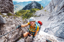 Smiling Caucasian Woman Mountaineer With Sunglasses On Via Ferrata Trail In The Alps On A Sunny Summer Day