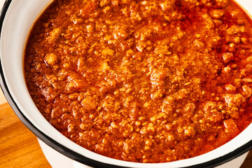 Close-up of fresh BOLOGNESE SAUCE in a white saucepan. High angle view.