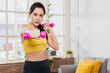 © khwanchai - Sporty young woman raises dumbbell, young Asian female exercising with her weights in the living room