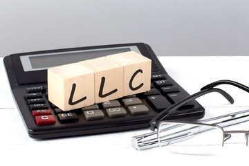 Poster - LLC concept on wooden cubes on calculator on white background