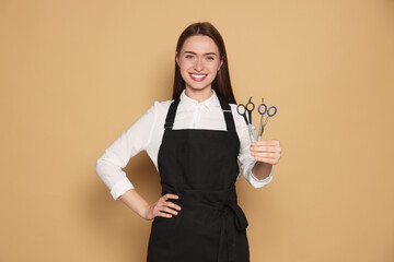 Poster - Portrait of happy hairdresser with professional scissors on beige background