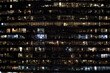 Frontal view of the night facade of building with a lot of windows with light. life in every window. night view of the glass facade of an office skyscraper.