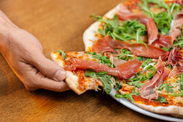 Wall Mural - fast food, italian kitchen and eating concept - close up of male hand taking pizza slice from plate