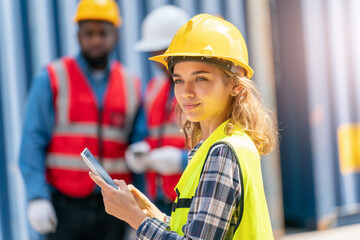 Women Engineer wears PPE checking container storage with cargo container background at sunset. Logistics global import or export shipping industrial concept.