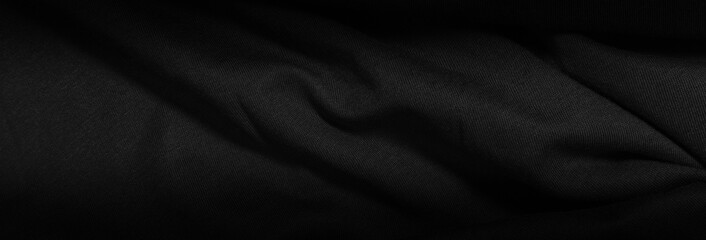 Dark background from a wavy fabric texture. Wide panoramic black background with space for design. Web banner, website header