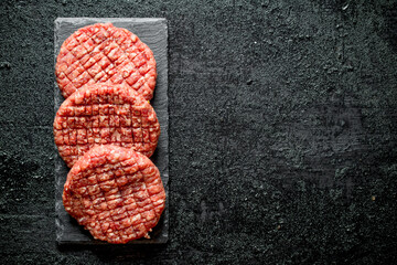 Poster - Raw burgers on a stone stand.