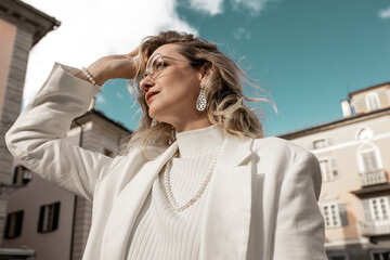 Wall Mural - Young beautiful woman outside, stylishly dressed, in jewelry, enjoys the good sunny weather.