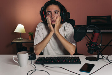 Young gamer or streamer guy frustrated touching his face with his fingers and rolling his eyes.