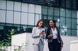 © Zamrznuti tonovi - Two multiracial business woman meeting outside in front of the office building