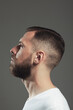 © Augustino - Male beauty concept. Profile portrait of charismatic active 30-year-old man posing over gray background. Perfect haircut. Poster style. Close up. Studio shot