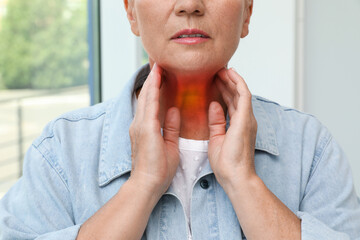 Wall Mural - Endocrine system. Mature woman doing thyroid self examination indoors